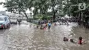 Anak-anak bermain air saat sejumlah kendaraan terjebak kemacetan akibat banjir yang menggenangi Jalan Jatinegara Barat, Jakarta, Senin (8/2/2021). Selain menyebabkan pertokoan di kawasan itu terpaksa tutup, banjur juga menggangu aktivitas warga. (merdeka.com/Iqbal S. Nugroho)