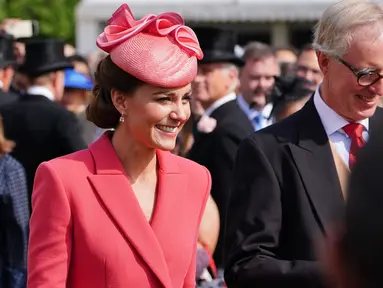 Kate Middleton, Duchess of Cambridge dari Inggris berbicara kepada para tamu di Pesta Taman Kerajaan di Istana Buckingham di London (18/5/2022). Kate Middleton tampak anggun dalam gaun mantel versi koral berwarna merah muda. (AFP/Pool/Dominic Lipinski)