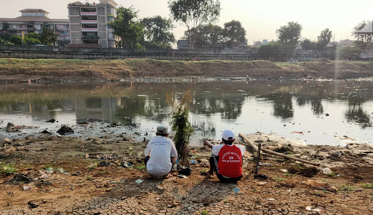 Warga memancing di sekitar Kanal Banjir Barat (KBB) yang mengalami kekeringan di kawasan Tanah Abang, Jakarta, Jumat (12/7/2019). Musim kemarau yang terjadi di Ibu Kota menyebabkan debit air di KBB berkurang sehingga menimbulkan keretakan tanah di sekitarnya. (Liputan6.com/Immanuel Antonius)