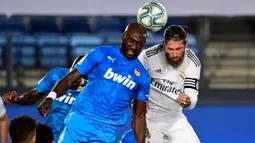 Bek Real Madrid, Sergio Ramos, bebrebut bola dengan bek Valencia, Eliaquim Mangala, pada laga lanjutan La Liga Spanyol pekan ke-29 di Stadion Alfredo, Stefano, Jumat  (19/6/2020) dini hari WIB. Real Madrid menang 3-0 atas Valencia. (AFP/Javier Soriano)