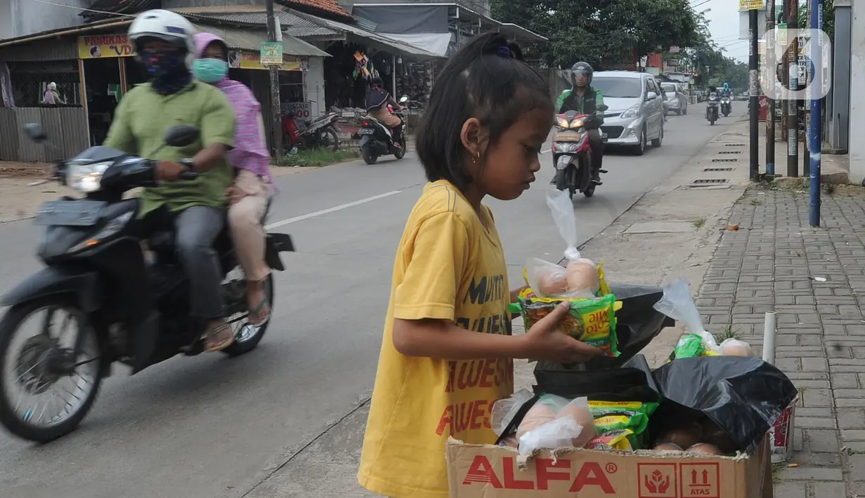 Seorang anak mengambil mi instan dan telur gratis di Jalan Raya Cibubur-Bojong Kulur, Bogor, Kamis (9/4/2020). Di beberapa pinggir jalan Kawasan Jabotabek saat ini banyak aksi solidaritas oleh warga dengan menyediakan bahan makanan gratis di tengah pandemi virus corona. (merdeka.com/Arie Basuki)