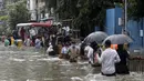 Orang-orang berjalan melewati jalan yang tergenang air setelah hujan lebat di Mumbai, India, Rabu (23/9/2020). Musim hujan di India berlangsung dari Juni hingga September. (AP Photo/Rajanish Kakade)