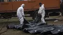 Pekerja pemakaman membawa jasad seorang pria dari kuburan massal untuk diidentifikasi di kamar mayat, di Bucha, di pinggiran Kiev, Ukraina, Minggu, 10 April 2022. Invasi Rusia ke Ukraina hingga saat ini telah berlangsung selama 46 hari.  (AP Photo/Rodrigo Abd)