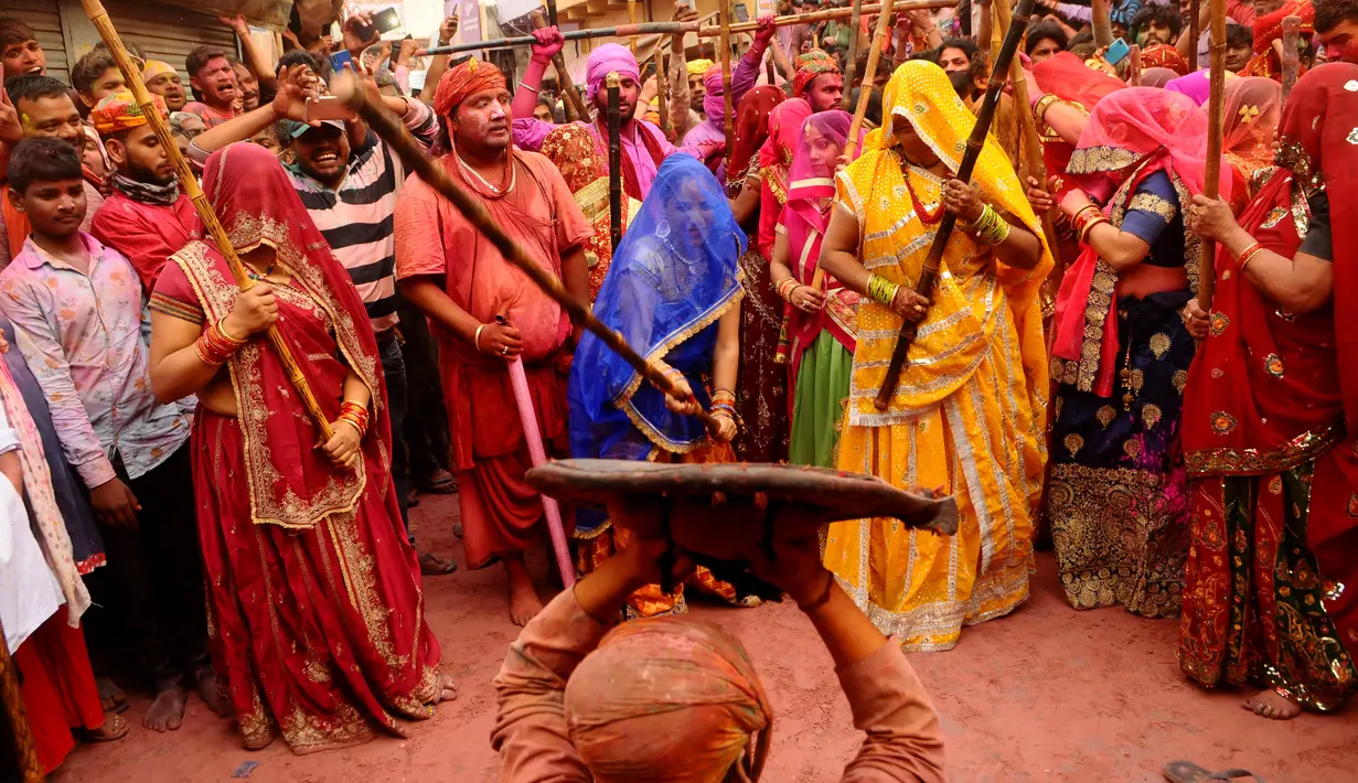 Perempuan India dari desa Barsana memukuli seorang warrga dari Nandgoan dengan tongkat kayu selama perayaan festival Lathmar holi di Barsana, India, Selasa (23/3/2021). Para pria biasanya membawa perisai untuk melindungi diri mereka sendiri sementara wanita memukuli mereka dengan tongkat. (AP Photo)