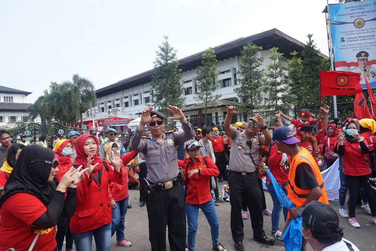 Para polisi menari menemani para demonstran saat peringatan Hari Buruh Sedunia di depan Gedung Sate Bandung.