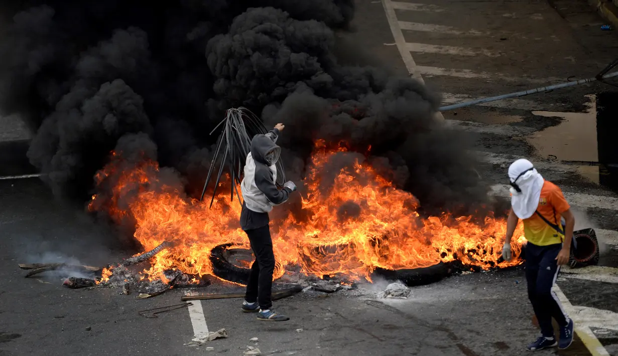Demonstran dari oposisi Venezuela berada didekat kobaran api saat menggelar aksinya menentang Presiden Nicolas Maduro di Caracas, Venezuela (24/4). (AFP/Federico Parra)