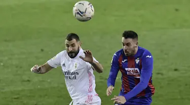 Penyerang Real Madrid, Karim Benzema dan gelandang Eibar, Edu Exposito berebut bola pada laga lanjutan Liga Spanyol di Stadion Ipurua, Senin dinihari WIB (21/12/2020). Benzema menjadi pahlawan dalam kemenangan Madrid karena menciptakan satu gol dan dua assist di laga tersebut. (AP/Alvaro Barrientos)