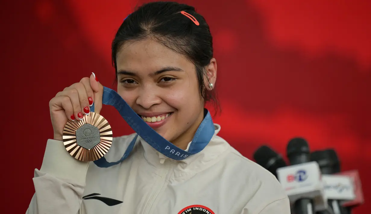 Peraih medali perunggu cabang olahraga bulu tangkis tunggal putri Olimpiade Paris 2024, Gregoria Mariska Tunjung berfoto dengan medali yang diraihnya di Istana Merdeka, Jakarta, pada Kamis 15 Agustus 2024. (BAY ISMOYO/AFP)