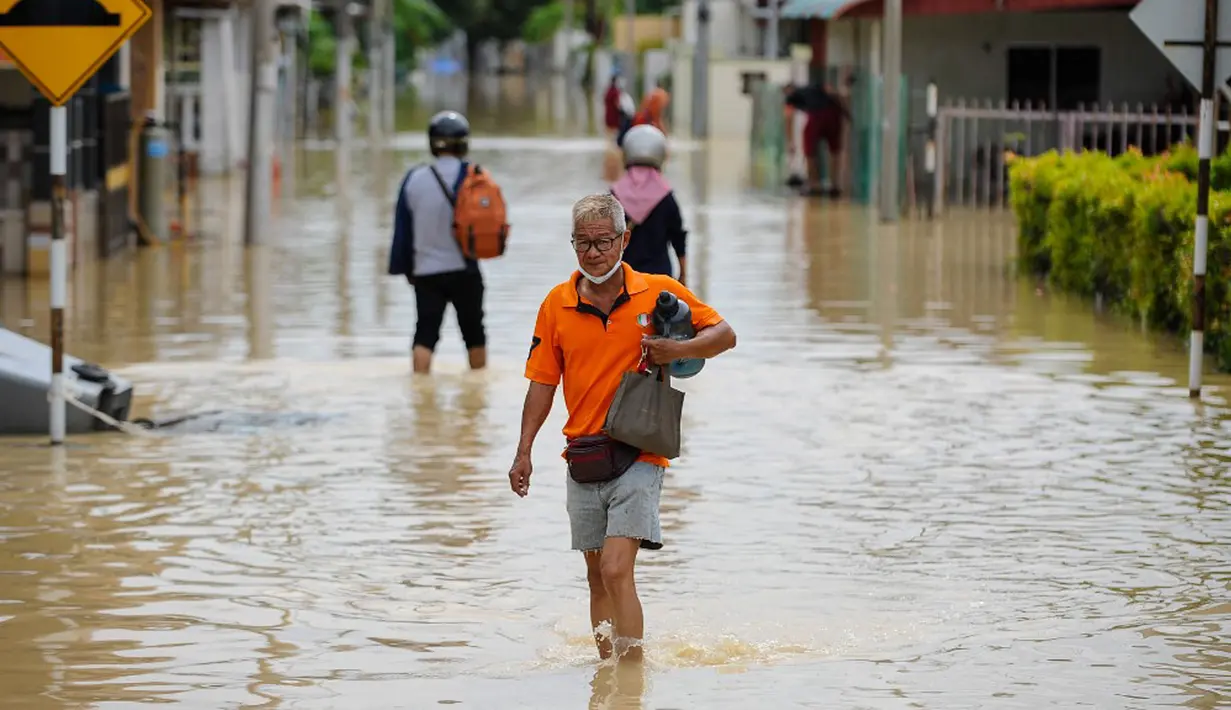 Warga mengarungi banjir di Batu Berendam, Malaka, Malaysia, 3 Januari 2022. Dilaporkan AsiaOne, Selasa (4/1/2022) ada tujuh negara bagian Malaysia yang terdampak, yakni Kelantan, Terengganu, Pahang, Johor, Malacca, Negeri Sembilan dan Sabah. (NAZRULHAD HASHIM/AFP)