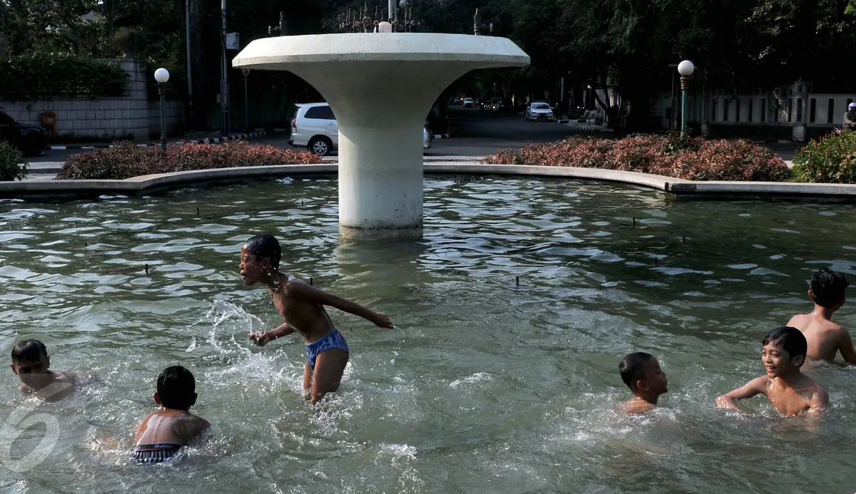 Anak-anak  berenang di kolam air mancur di kawasan Jalan Diponogoro, Jakarta, Jumat (31/7/2015). Minimnya lahan bermain di Ibukota, membuat mereka memanfaatkan kolam air mancur sebagai tempat berenang. (Liputan6/Johan Tallo)