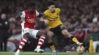 Penyerang Arsenal Bukayo Saka berebut bola dengan bek Wolverhampton Wanderers Rayan Ait-Nouri pada partai tunda pekan ke-20 Liga Inggris di Emirates Stadium, Jumat (25/2/2022) dini hari WIB. Arsenal menang dramatis 2-1 berkat dua gol di menit akhir. (AP Photo/Ian Walton)
