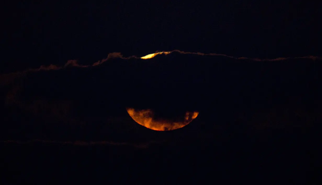 Pemandangan ketika supermoon terbenam di balik awan di laut Mediterania di lepas pantai Hadera, Israel, Rabu (31/1). (AP Photo/Ariel Schalit)