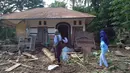 Para wanita berjalan melewati rumah yang rusak akibat banjir bandang di Waiwerang, Pulau Adonara, Nusa Tenggara Timur, Selasa (6/4/2021). Tim penyelamat terus menggali puing tanah longsor untuk mencari korban yang terkubur usai bencana banjir bandang. (AP Photo/Rofinus Monteiro)