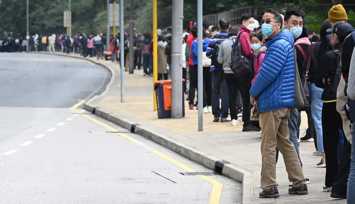 Antrean panjang orang di jalan untuk stasiun pengumpulan spesimen bergerak untuk pengujian Covid-19 di distrik Tung Chung, Hong Kong pada 10 Februari 2022. Antrean terjadi ketika pihak berwenang bergegas untuk meningkatkan kapasitas pengujian menyusul rekor jumlah infeksi baru. (Peter PARKS / AFP)