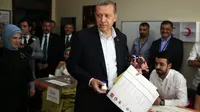 Presiden Turki Recep Tayyip Erdogan saat memberikan suara bersama sang istri. (BBC)