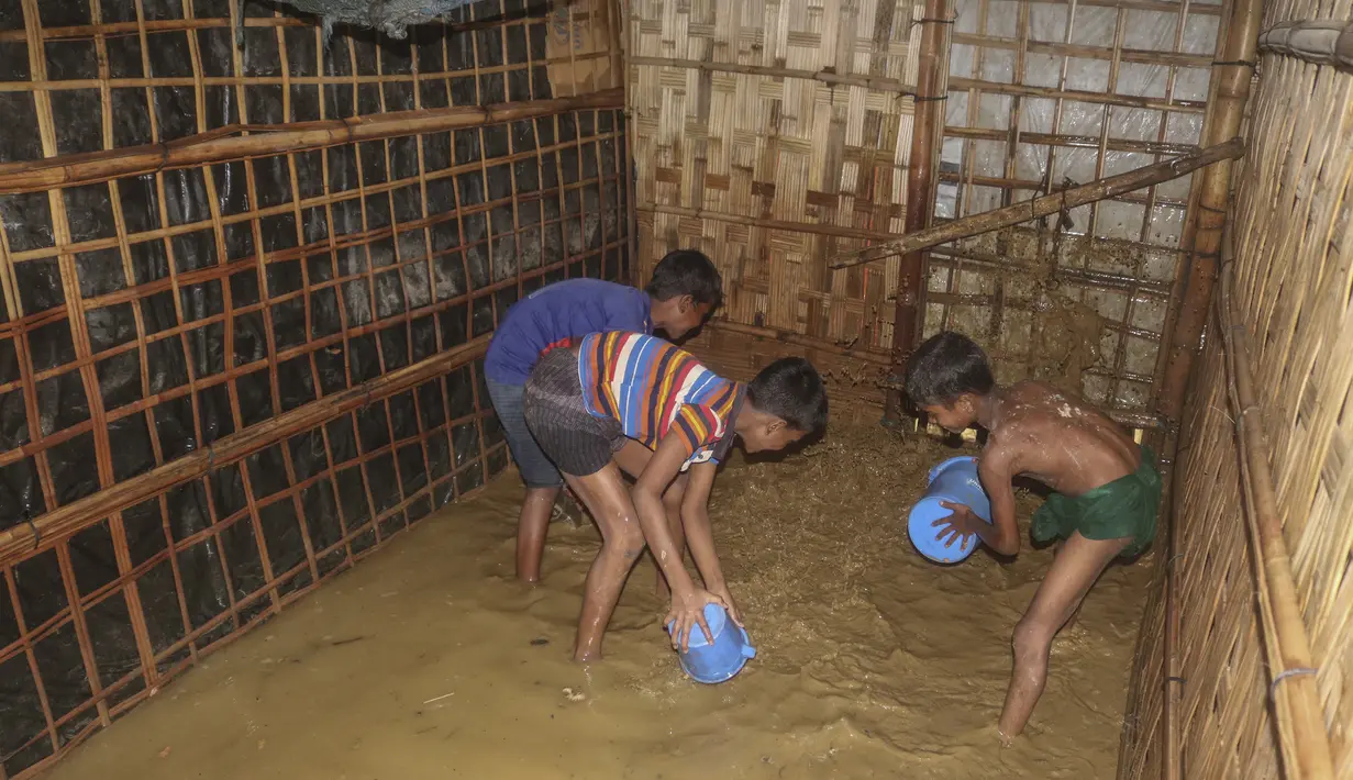 Anak-anak pengungsi Rohingya mengeluarkan air banjir dari rumah mereka di kamp pengungsi Rohingya di Kutupalong, Bangladesh (28/7/2021). Ribuan pengungsi kehilangan tempat tinggal akibat banjir tersebut. (AP Photo/Syafiqur Rahman)
