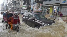 Para penumpang melewati jalan yang dilalui air setelah hujan lebat di Dhaka (21/7/2020). Korban tewas akibat hujan lebat di Asia Selatan telah meningkat menjadi hampir 200, ketika Bangladesh dan Nepal memperingatkan bahwa naiknya air akan membawa banjir lebih lanjut. (AFP/Munir Uz zaman)