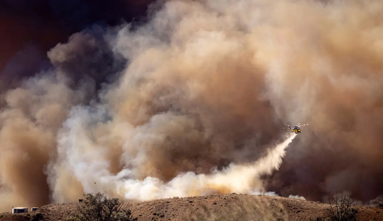 Sebuah helikopter pemadam kebakaran melakukan upaya pemadaman di atas kebakaran gunung (mountain fire) yang menghanguskan puluhan hektar lahan di Santa Paula, California, pada tanggal 7 November 2024. (ETIENNE LAURENT/AFP)