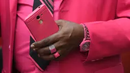 Fashionista Kenya, James Mwangi Maina memegang ponselnya sambil memamerkan setelan jasnya yang senada dengan pakaian dan aksesorisnya, termasuk masker di jalanan Nairobi, 5 Agustus 2020. Mwangi mengklaim dirinya memiliki penampilan terbaik dan paling stylish di Afrika. (Simon MAINA/AFP)