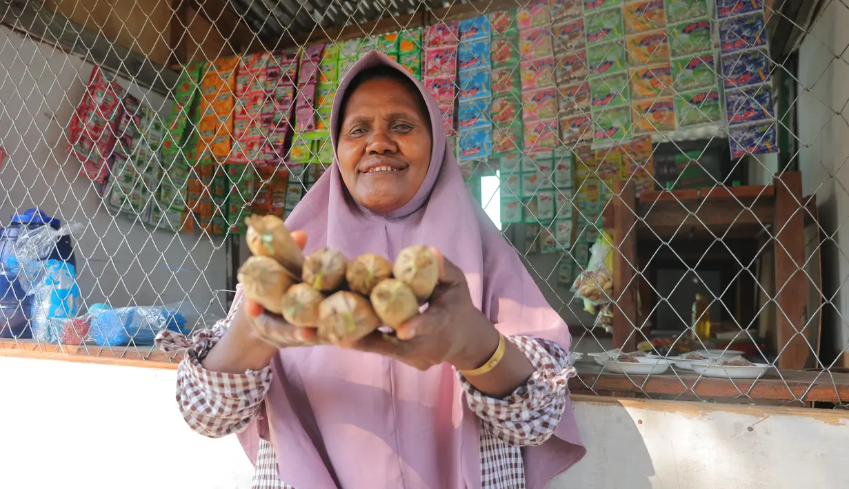 Ragaia Sosir menunjukkan terasi yang dijual di kiosnya. Sebelum membuka kios dan menjadi BRILink Agen, ia mengandalkan hasil melaut bersama suami dan mengolah udang menjadi terasi untuk menambah penghasilan keluarga. (Sumber: BRI/Advertorial)