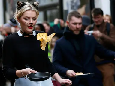 Seorang peserta ikut ambil bagian dalam acara tahunan Great Spitalfields Pancake Race untuk mengumpulkan uang bagi Ambulan Udara London di Inggris, Selasa (9/2). (REUTERS/Stefan Wermuth)