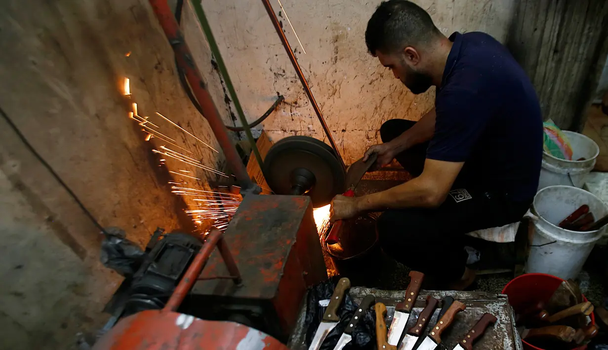 Seorang pria Palestina menajamkan pisau yang akan digunakan untuk menyembelih hewan kurban dalam perrayaan Idul Adha di sebuah lokakarya di Kota Gaza, 28 Juli 2020.  Idul Adha merupakan salah satu tanggal penting dalam kalender Islam. (AP Photo/Hatem Moussa)