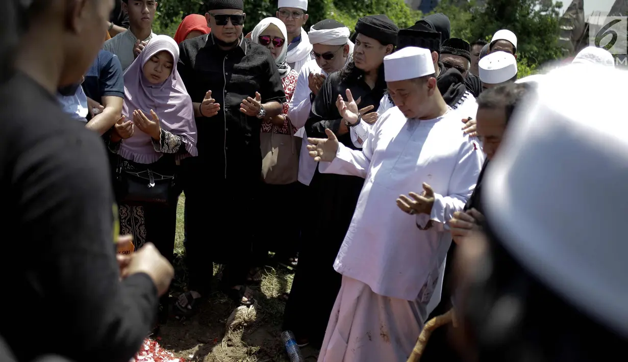 Penyanyi Opick berdoa di samping makam istri keduanya Wulan Mayasari di TPU Semper, Jakarta, Senin (19/3). Selama proses pemakaman ini, Opick didampingi oleh para santri dan kerabat dari perkumpulan komunitas bela diri. (Liputan6.com/Faizal Fanani)