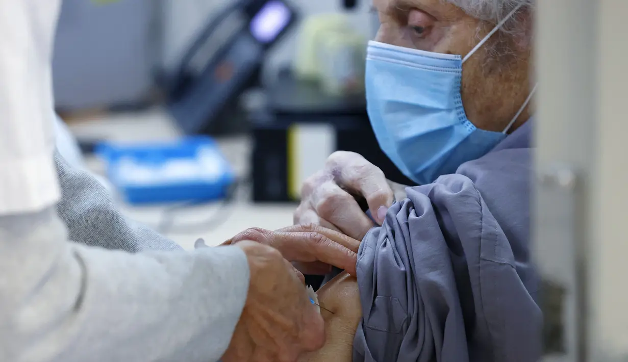 Seseorang menerima dosis keempat vaksin covid-19 Pfizer-BioNTech di Clalit Healthcare Services di Tel Aviv, Senin (3/1/2022). Israel telah menyetujui dosis keempat kepada warga di atas 60 tahun dan tenaga kesehatan di tengah lonjakan kasus Covid-19 yang didorong oleh varian Omicron. (JACK GUEZ/AFP)