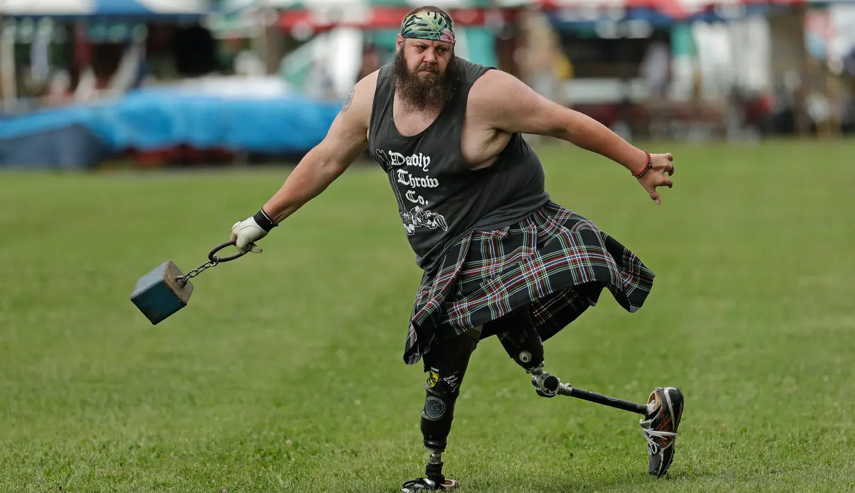 Matthew Hall melakukan pemanasan sebelum melempar beban dalam Grandfather Mountain Highland Games ke-64 di MacRae Meadows, Linville, North Carolina, AS, Jumat (12/7/2019). Kejuaraan ini digelar untuk merayakan sejarah dan budaya Skotlandia. (AP Photo/Chuck Burton)