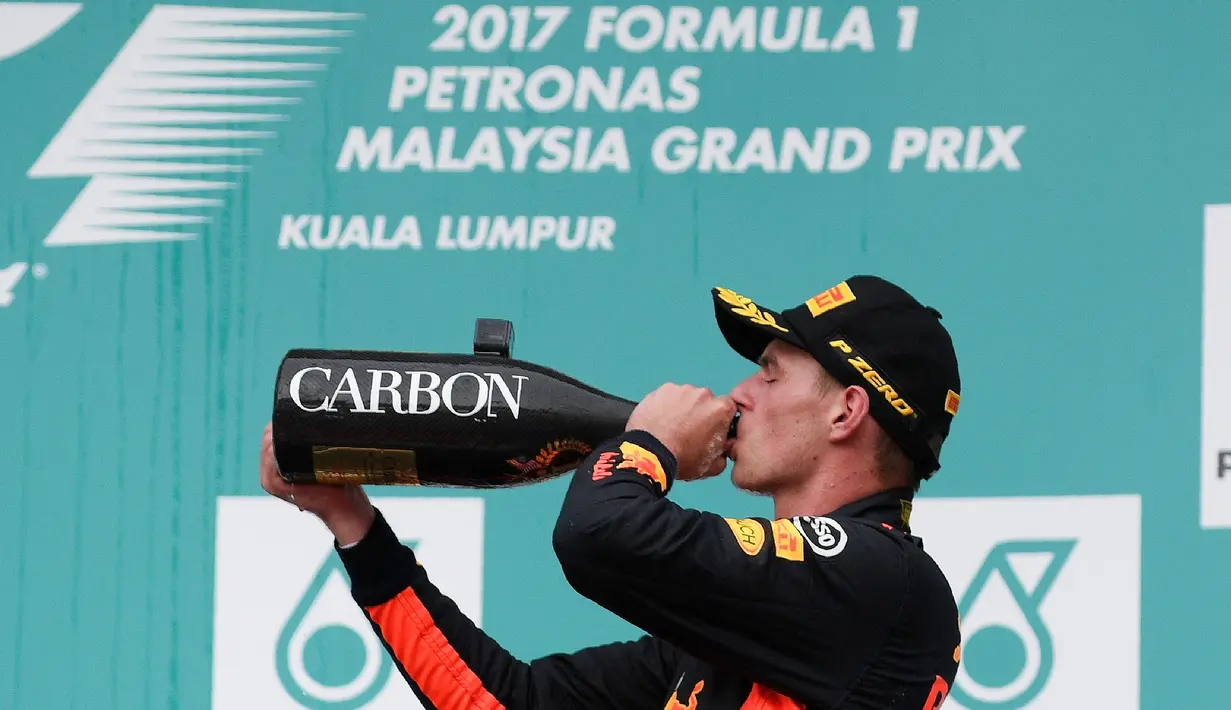 Pembalap Red Bull asal Belanda, Max Verstappen merayakan kemenangan dengan minum sampanye di podium setelah menjuarai Formula 1 Grand Prix Malaysia di Sepang, Minggu (01/10) (AFP PHOTO / MANAN VATSYAYANA)