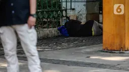 Kondisi seseorang yang tergeletak di Jalan Merdeka Barat, Jakarta, Kamis (23/4/2020). Usai dilakukan pemeriksaan oleh tim medis yang menggunakan alat pelindung diri (APD), tunawisma tersebut dinyatakan negatif covid-19. (Liputan6.com/Faizal Fanani)