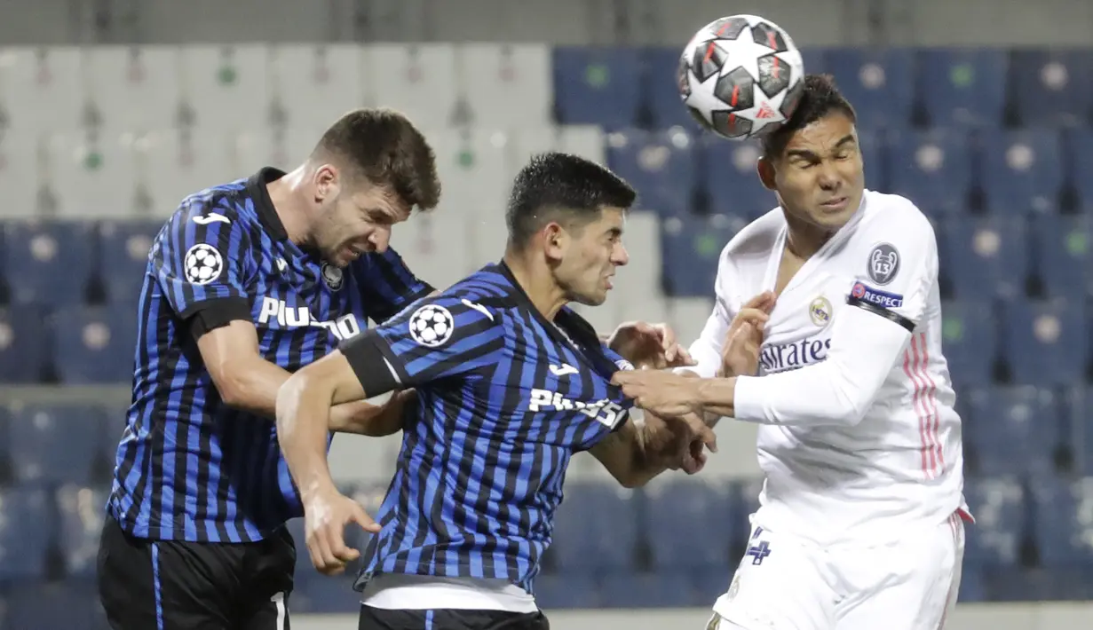 Gelandang Real Madrid, Casemiro menyundul bola melewati pemain Atalanta, Cristian Romero dan Berat Djimsiti  pada leg pertama babak 16 besar Liga Champions di Stadion Gewiss, Kamis (25/2/2021) dini hari WIB. Real Madrid harus susah payah kalahkan Atalanta 1-0. (AP Photo/Luca Bruno)