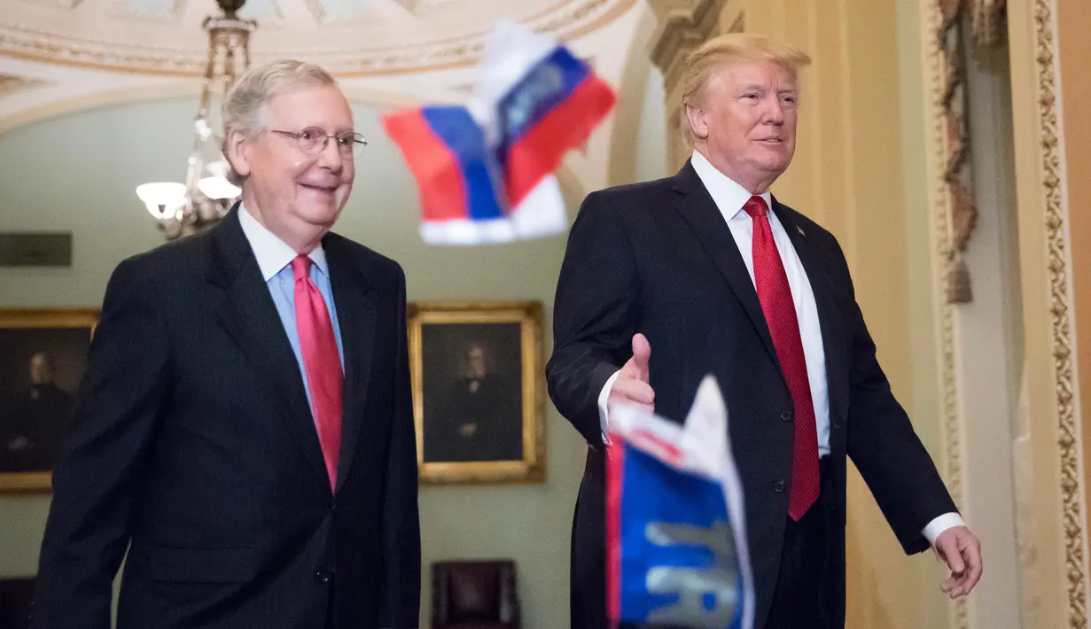 Bendera Rusia dilemparkan ke arah Presiden AS, Donald Trump yang berjalan bersama senator Mitch McConnel di Capitol Hill, Washington DC, Selasa (24/10). Pada saat itu, Trump hendak hadir di acara makan siang rutin dengan senator. (AP/J. Scott Applewhite)
