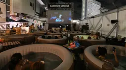 Pengunjung menikmati menonton film sambil berendam di Bathtub Cinema di atap gedung kawasan Shibuya, Tokyo, 17 Agustus 2018. Penyelenggara menyediakan 12 bak mandi bundar yang setiap bathtubnya dapat diisi oleh empat orang. (AFP/Kazuhiro NOGI)