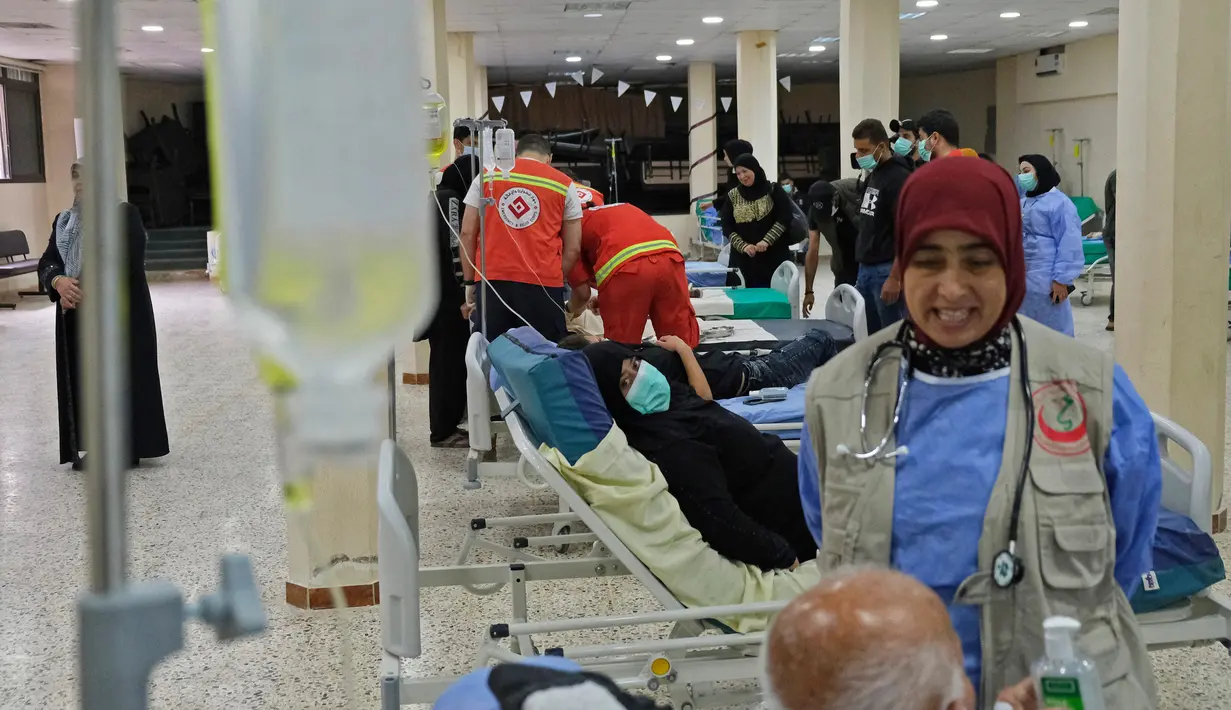 Staf medis merawat pasien yang dirawat akibat wabah kolera Vibrio di bangsal di aula masjid yang diubah menjadi rumah sakit lapangan di Kota Bebnine, Distrik Akkar, Lebanon Utara, Rabu (26/10/2022). Penularan Kolera akses air bersih dan fasilitas sanitasi yang buruk atau makanan yang terkontaminasi. (AFP/Ibrahim Chalhoub)