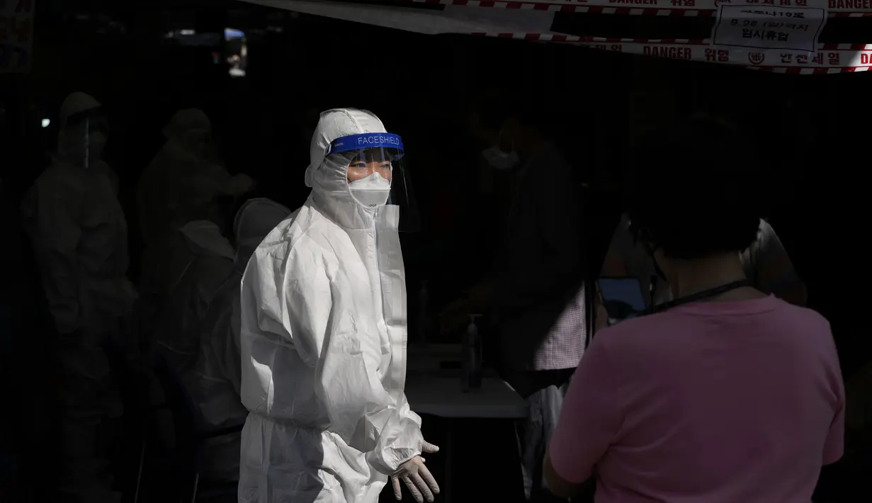 Petugas kesehatan mengenakan alat pelindung membantu pengunjung yang mengantre untuk mendapatkan tes virus corona di klinik skrining sementara virus corona di Seoul, Korea Selatan, Jumat (24/9/2021). (AP Photo/Lee Jin-man)