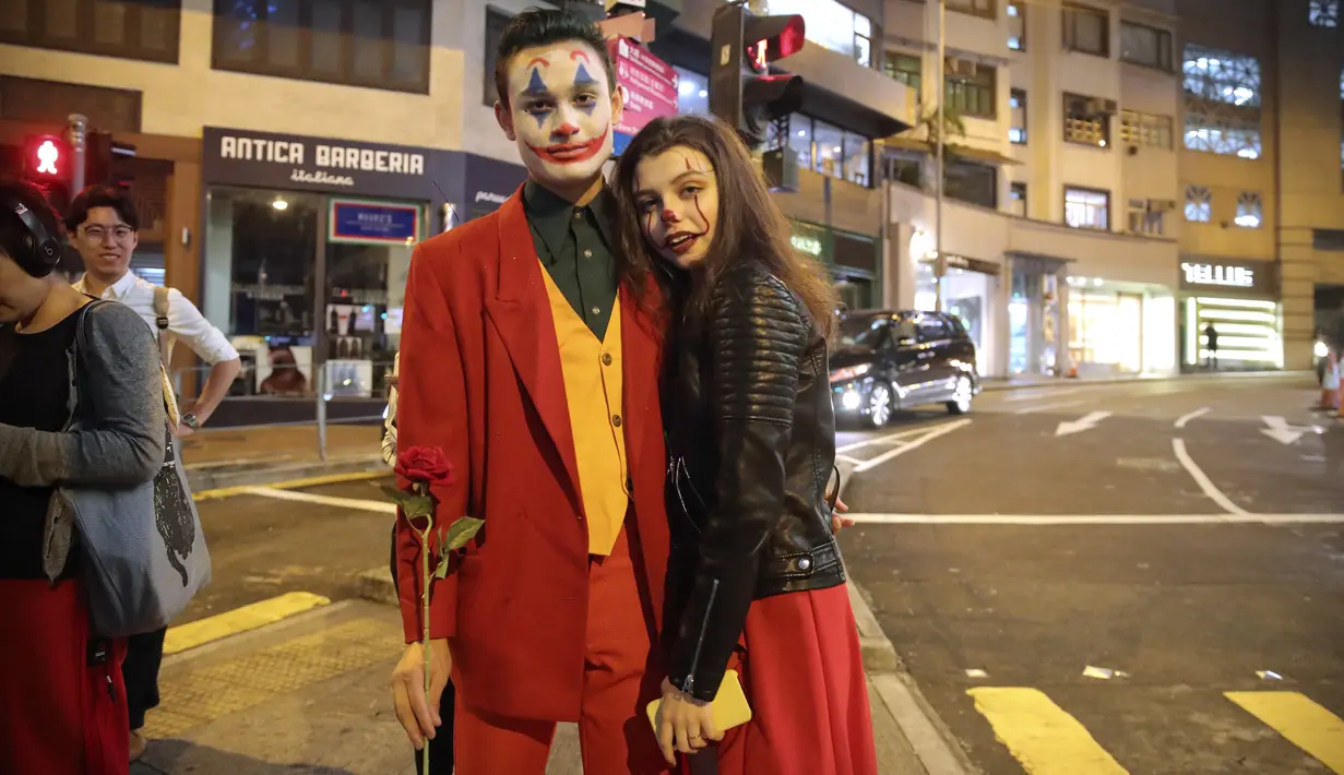 Pasangan mengenakan kostum Halloween berdiri di sebuah jalan di Hong Kong, Kamis (31/10/2019). Polisi Hong Kong bersiap untuk berjaga unjuk rasa Kamis malam, yang akan menguji peraturan larangan pemerintah untuk menutup wajah yang diperkenalkan bulan ini. (AP Photo/Kin Cheung)