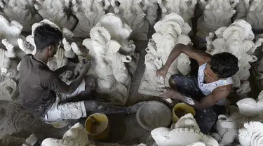 Para perajin menyelesaikan pembuatan patung Dewa Ganesha di sebuah bengkel di pinggiran Hyderabad, India, Senin (29/6/2020). Patung Dewa Ganesha banyak ditemukan di berbagai penjuru India termasuk Nepal, Tibet, dan Asia Tenggara. (NOAH SEELAM/AFP)