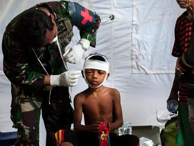 Petugas medis militer mengobati seorang anak laki-laki yang mengalami cedera akibat gempa Lombok di rumah sakit darurat di Kayangan, Rabu (8/8). BPBD Lombok Utara mencatat data sementara jumlah korban jiwa mencapai 347 orang. (AP/Fauzy Chaniago)