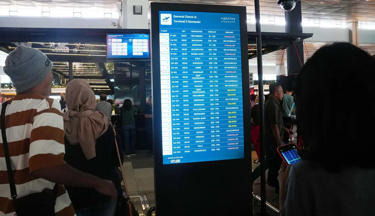 Calon penumpang berjalan melewati papan informasi yang menunjukkan penerbangan terganggu di Bandara Internasional Soekarno-Hatta di Tangerang, Indonesia, Minggu, 6 September 2026. (AP Photo/Tatan Syuflana)
