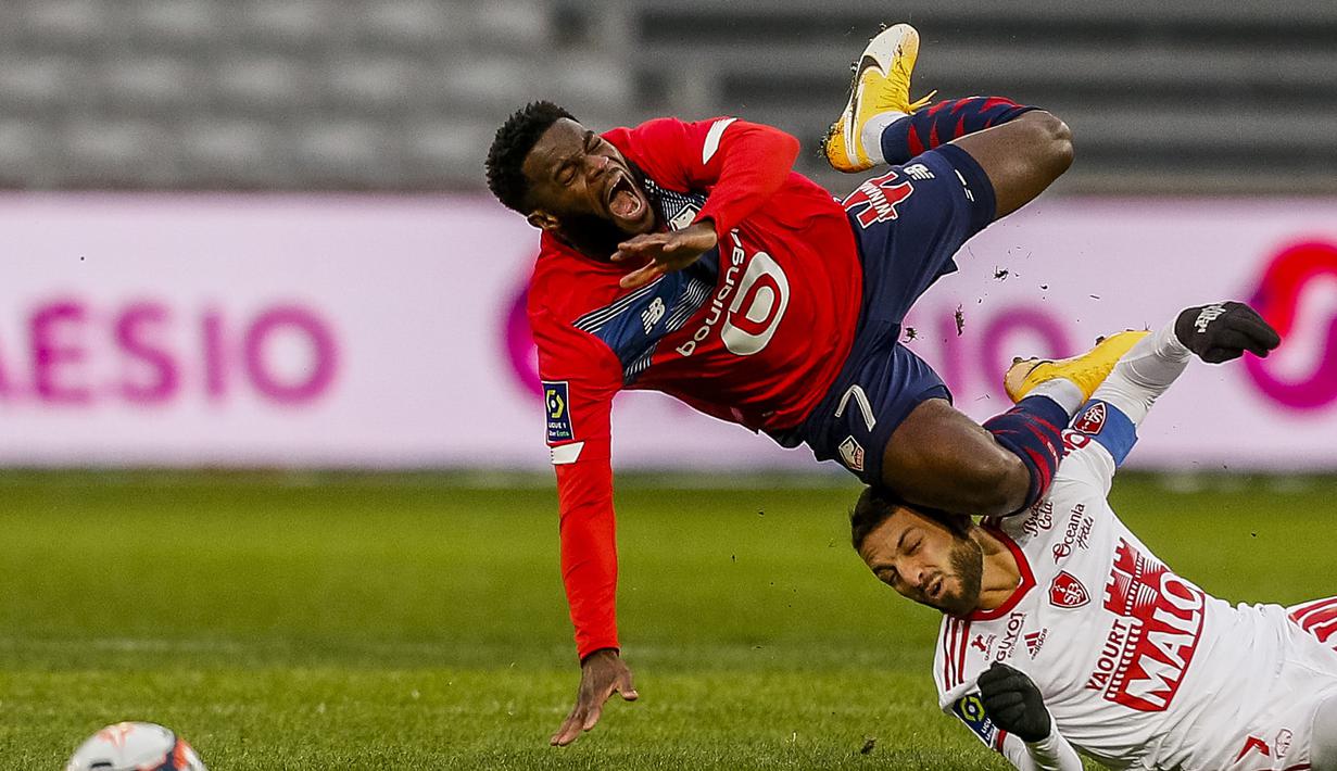 Striker Lille, Jonathan Bamba (atas) terjatuh ditekel gelandang Brest, Paul Lasne dalam laga lanjutan Liga Prancis 2020/21 pekan ke-25 di The Stade Pierre Mauroy, Lille, Minggu (14/2/2021). Lille bermain imbang 0-0 dengan Brest. (AP/Michel Spingler)