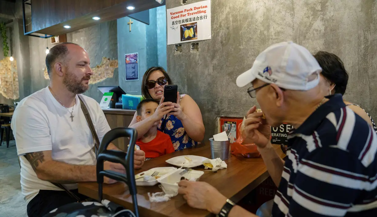 Keluarga makan durian di kafe Mao Shan Wang di Singapura (23/1). Restoran yang menyediakan beragam aneka rasa durian ini telah menarik banyak pengunjung untuk datang mencicipi buah durian di kafe tersebut. (AFP Photo/Nicholas Yeo)