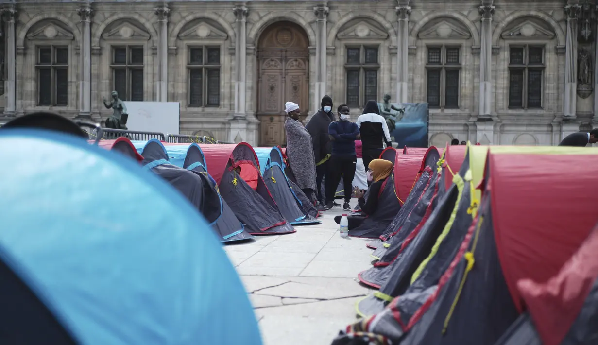 Para imigran berdiri di sebuah kamp darurat yang dibangun di luar balai kota Paris, pada Jumat (25/6/2021). Lebih dari 300 migran mendirikan sekitar 200 tenda di luar balai kota untuk menarik perhatian terhadap kondisi mereka dan menuntut akomodasi. (AP Photo/Lewis Joly)