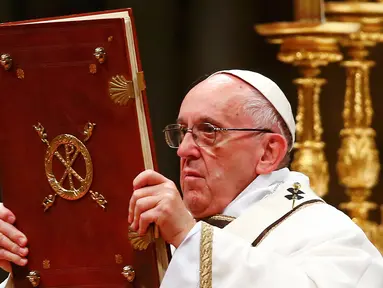 Paus Fransiskus memegang kitab Injil saat memimpin misa Natal di Basilika Santo Petrus, Vatikan, (24/12). Pada misa tersebut, Paus mengatakan bahwa Natal sudah "disandera" oleh materialisme. (REUTERS/Tony Gentile)