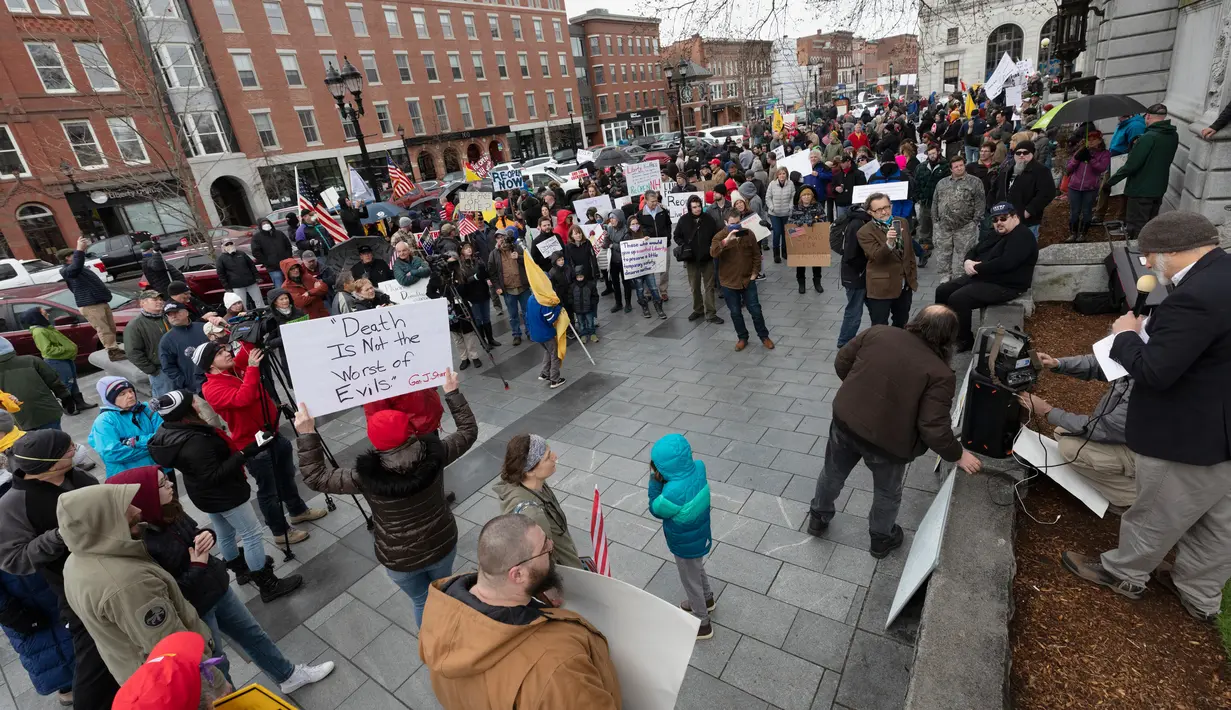 Orang-orang menghadiri demonstrasi untuk menyerukan pencabutan lockdown di State House di Concord, New Hampshire, Sabtu (18/4/2020).  Mereka meminta kebijakan yang ditujukan mencegah penyebaran COVID-19 segera dicabut, karena berdampak terhadap perekonomian. (AP/Michael Dwyer)