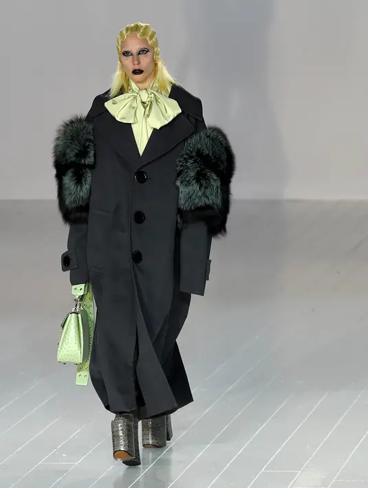 Peraih Golden Globe ini tampak mencolok mengenakan wig pirang, mantel kebesaran berwarna abu-abu serta dasi kupu-kupu dengan ukuran besar pula. Lady Gaga menjinjing tas tangan sebagai pelengkap penampilannya. (AFP/Bintang.com)