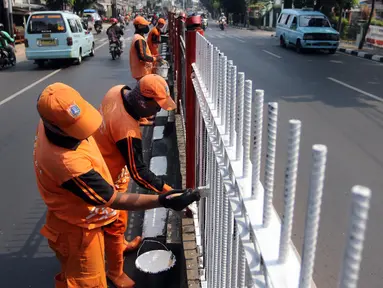 Petugas PPSU Kelurahan Kramat Jati melakukan pengecatan ulang pagar pembatas Jalan Raya Bogor, Jakarta, Selasa (17/7). Upaya penataan sekaligus mempercantik kawasan terus dilakukan jelang Asian Games dan Hari Kemerdekaan RI. (Liputan6.com/Arya Manggala)