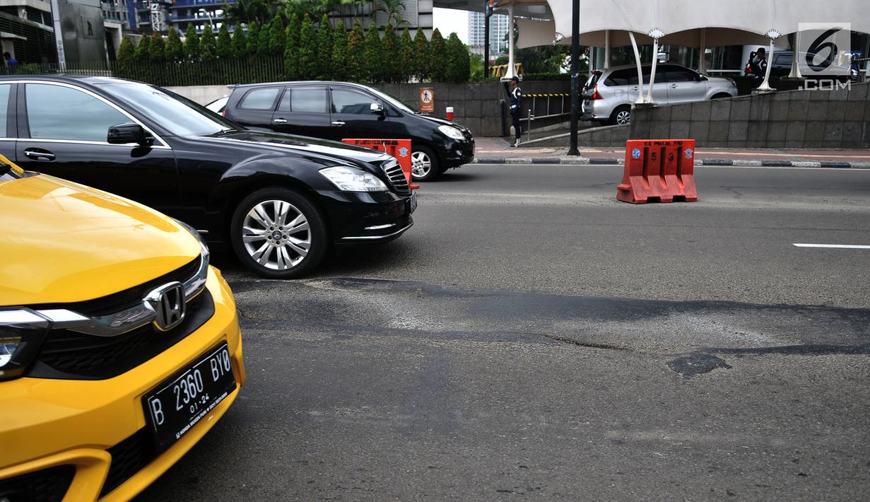 Kendaraan melintas di dekat jalan berlubang di Jalan Jenderal Sudirman, Jakarta, Senin (11/3). Jalanan di pusat kota tersebut berlubang dapat membahayakan keselamatan pengendara yang melintas. (merdeka.com/Iqbal S. Nugroho)