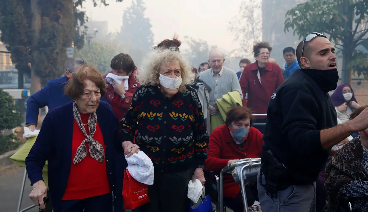 Sejumlah warga menyelamatkan diri saat asap kebakaran hutan mulai menyelimuti kawasan tempat tinggal mereka di Haifa, Israel, Kamis (24/11). Diduga 50 persen kebakaran hutan ini adalah faktor kesengajaan. (REUTERS / Baz Ratner)