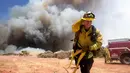 Petugas pemadam kebakaran berusaha memadamkan api di Cherry Valley, California (1/8/2020). Kebakaran lahan juga telah menjalar ke rumah penduduk. (AP Photo/Ringo H.W. Chiu)